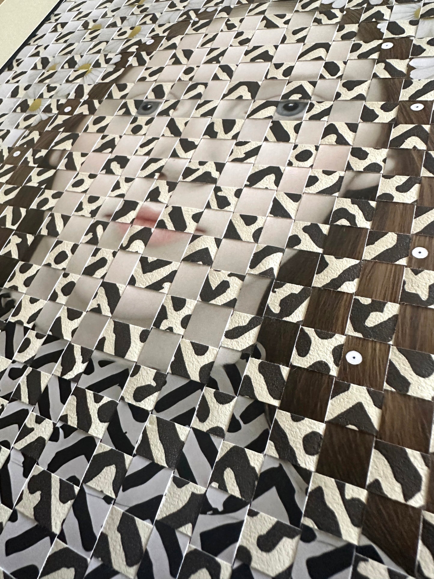 Patterned material with a mix of brown, black, and white woven with a portrait of a girl.