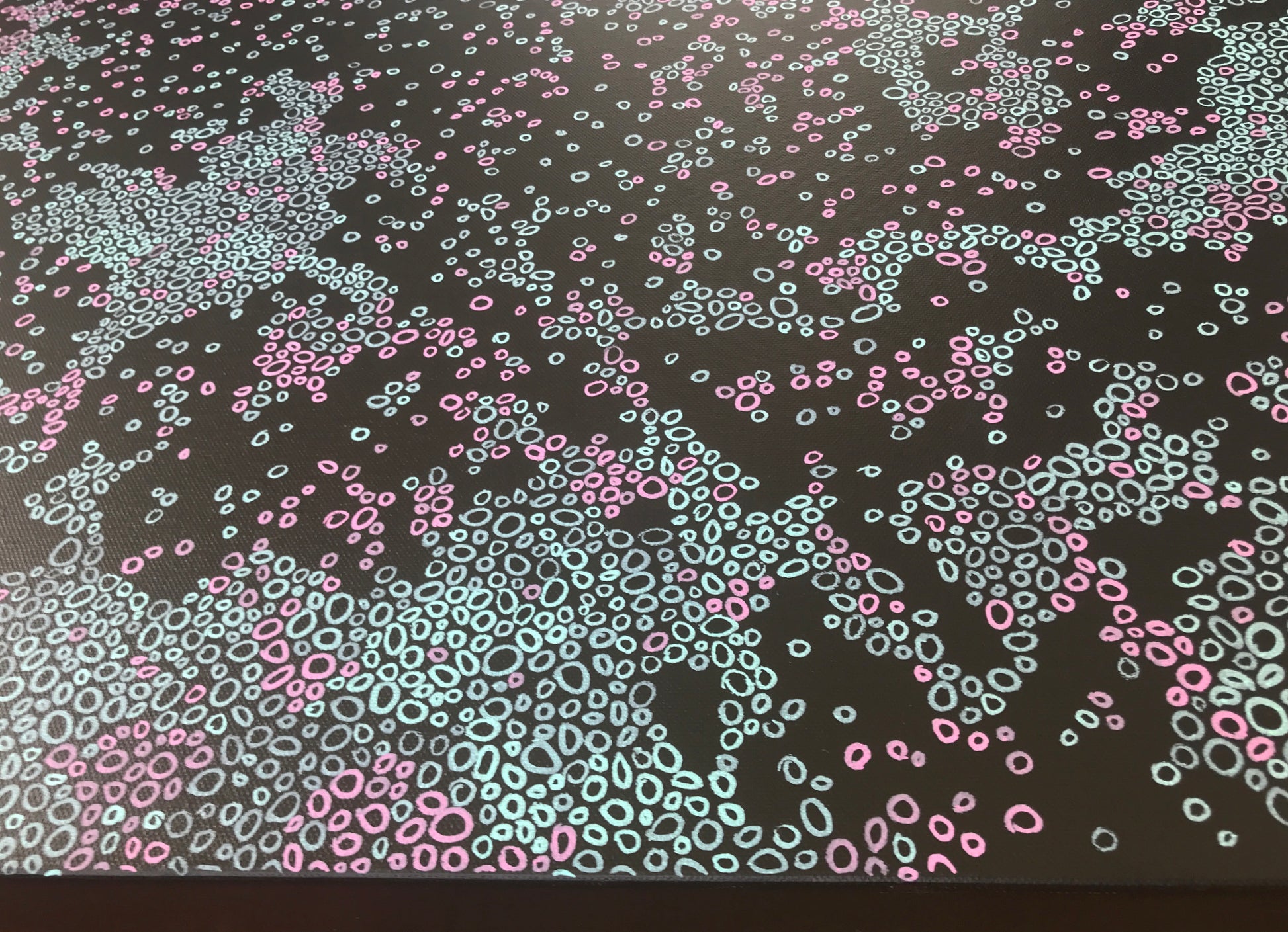 Detail of an abstract painting with soft pink and pale blue shapes scattered across a black background, inspired by visual snow and neural patterns.
