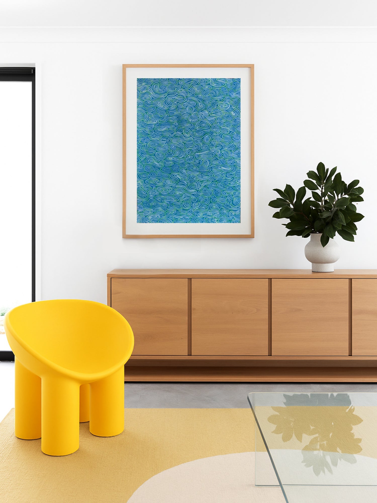Modern living room with a yellow huggy hair, wooden cabinet, and framed blue artwork.