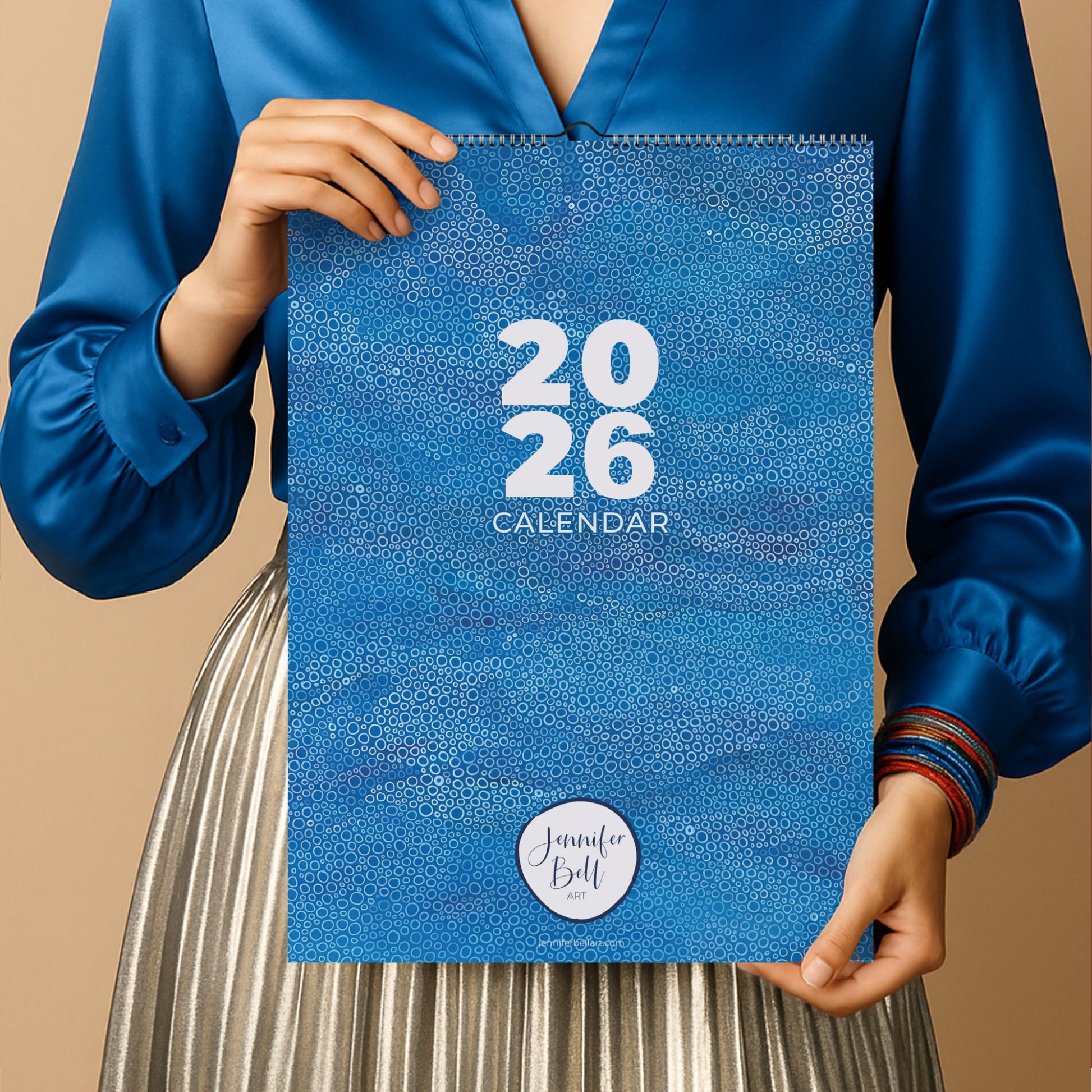 Person holding a blue abstract art calendar with '2026' printed on it 