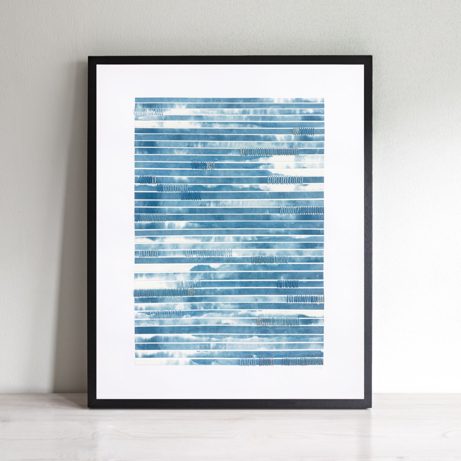 Abstract art with blue and white strips of paper and hand stitching