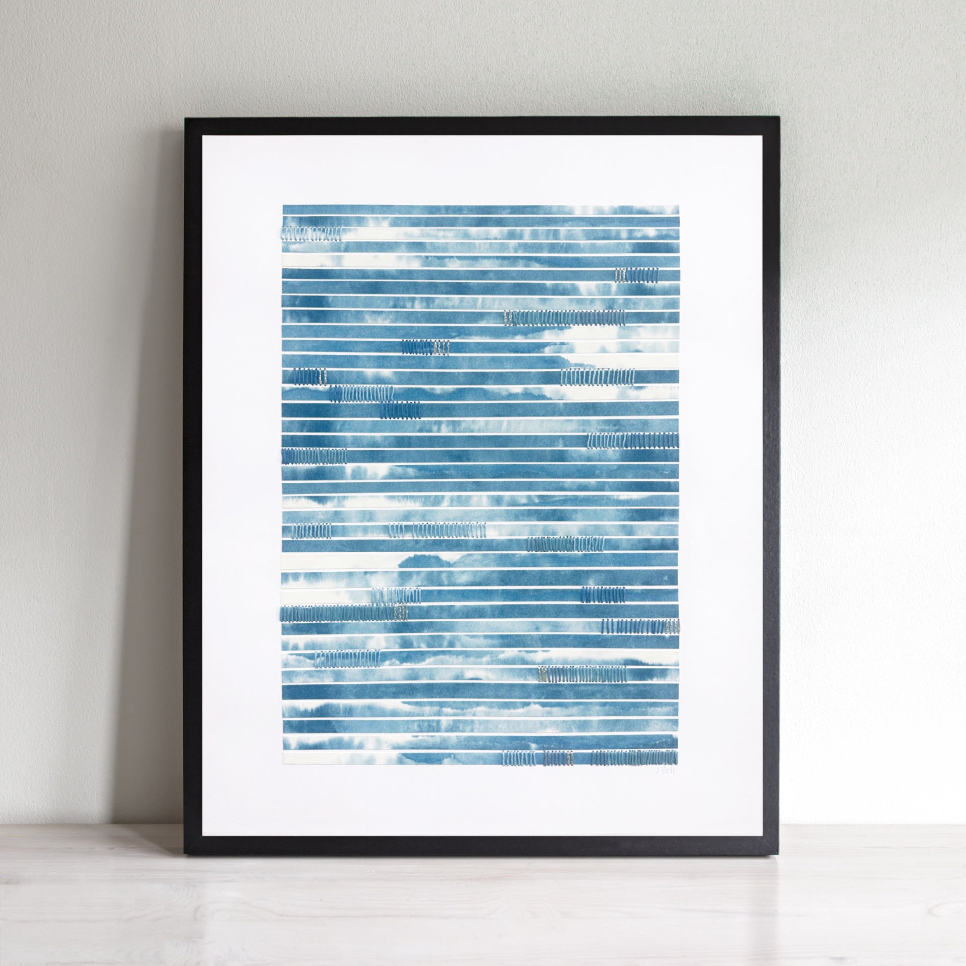 Abstract art with blue and white strips of paper and hand stitching