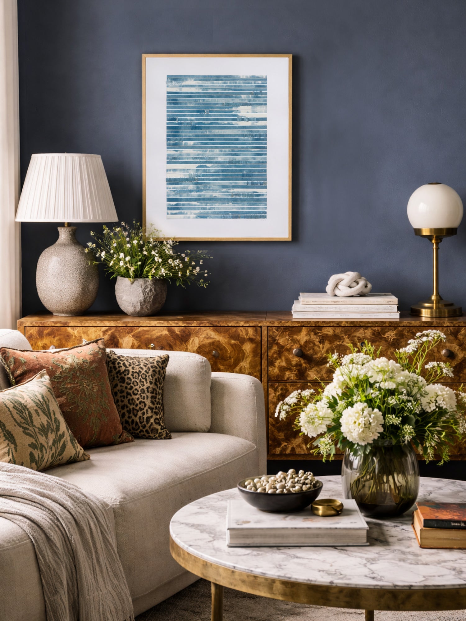 Blue abstract artwork in living room with a beige sofa, marble coffee table, and decorative items.
