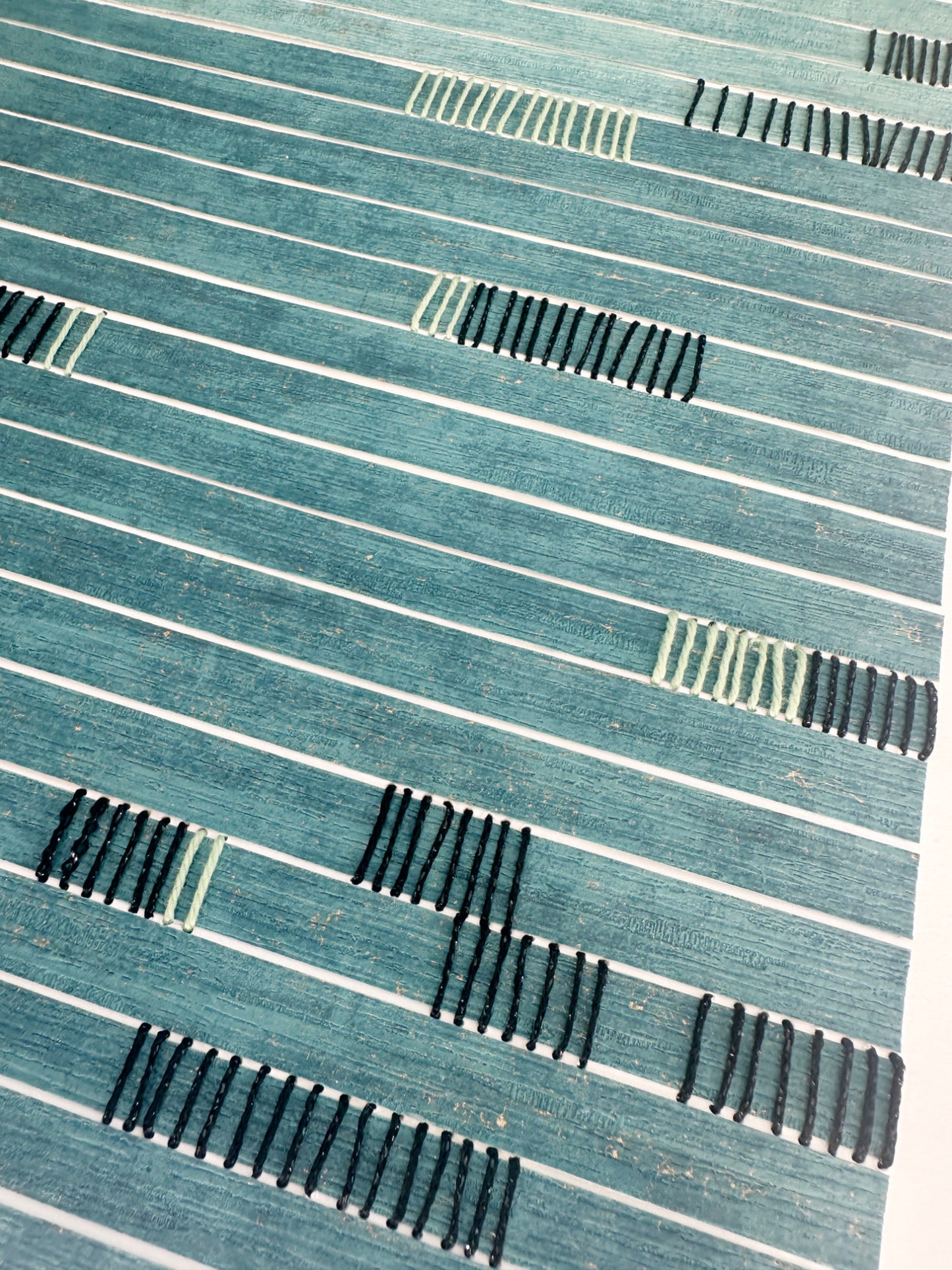 Textured paper artwork with black thread 