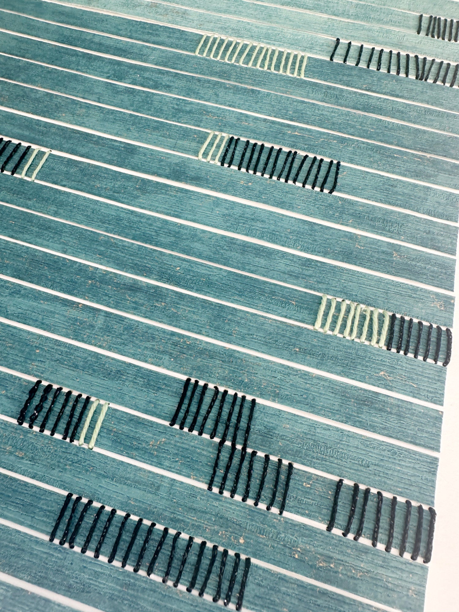 Textured paper artwork with black thread 