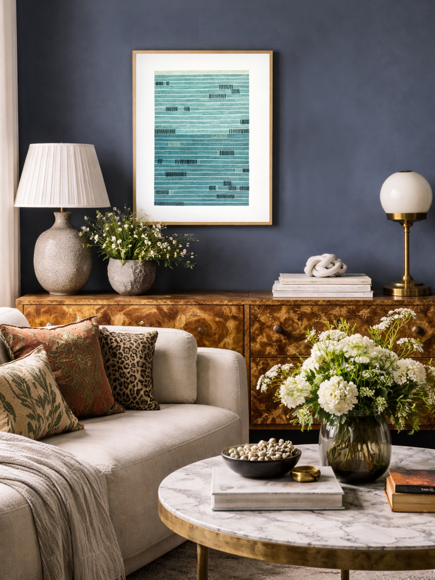 Living room with a couch, coffee table, and hand stitched paper art against a dark blue wall.