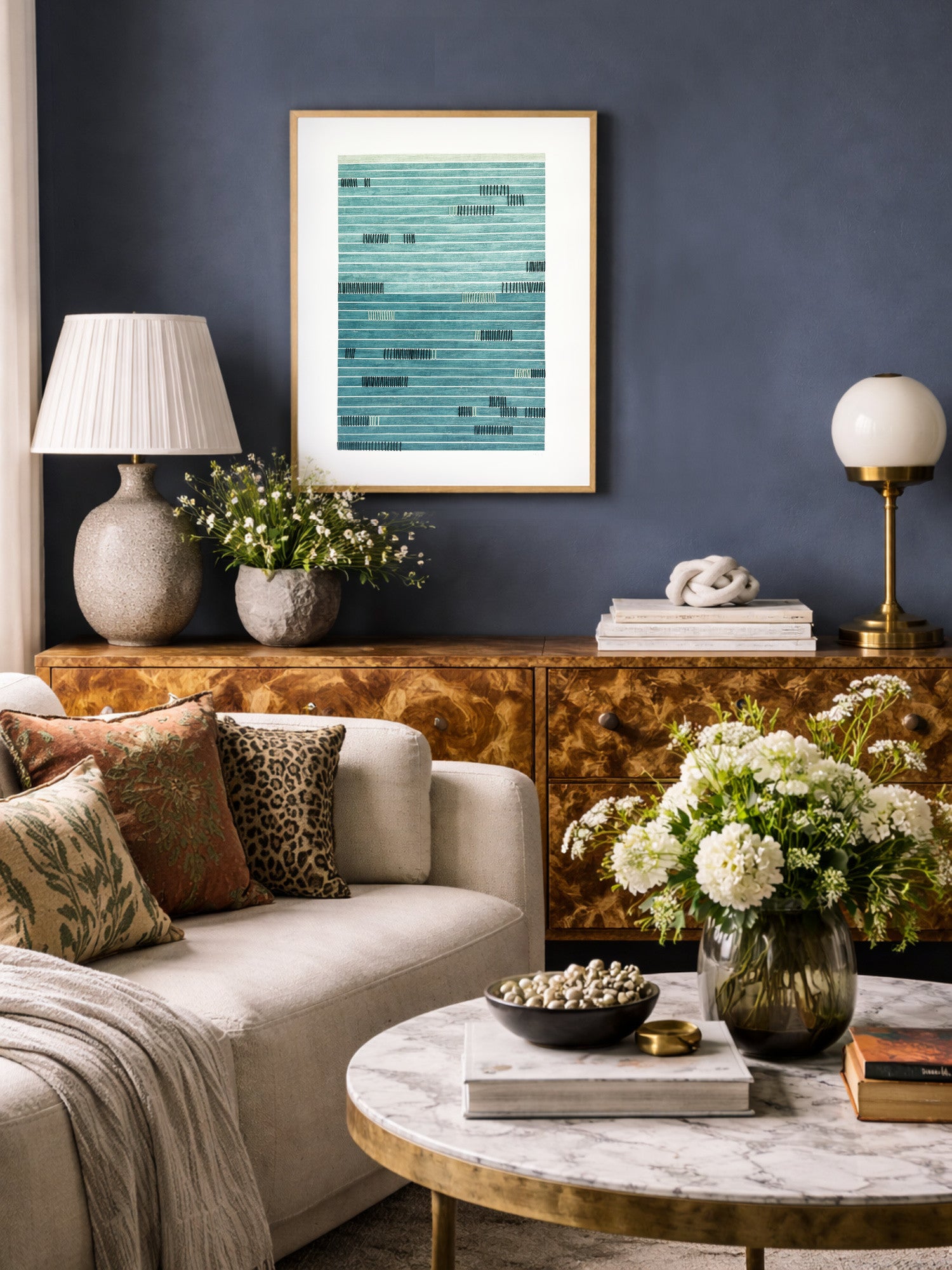 Living room with a couch, coffee table, and hand stitched paper art against a dark blue wall.