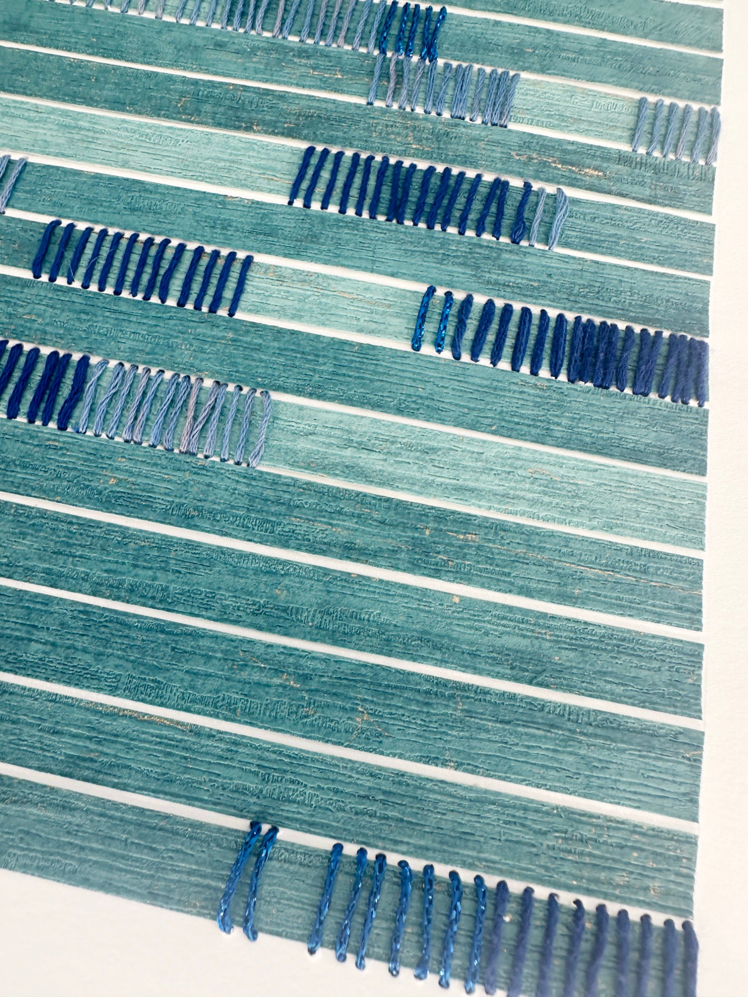 textured abstract wall art with blue and white stripes on a light background