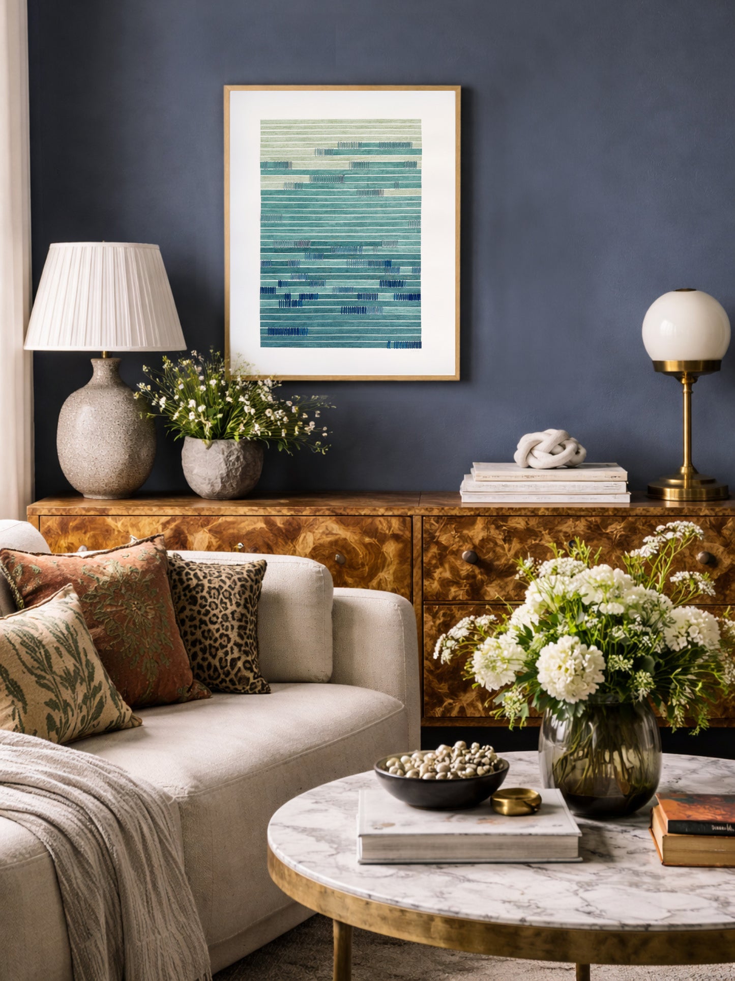 Living room with a sofa, coffee table, and contemporary abstract wall art against a dark blue wall.