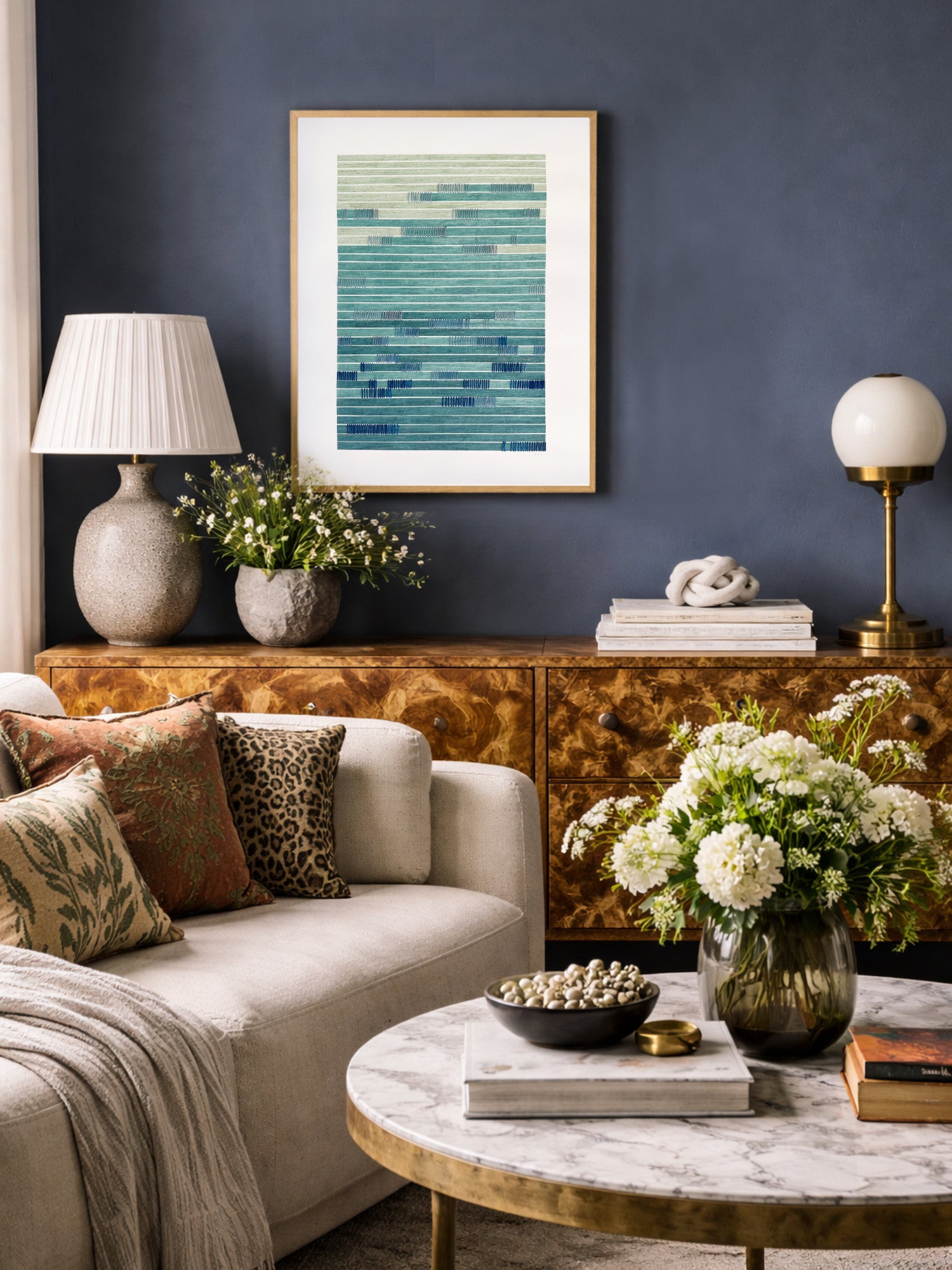Living room with a sofa, coffee table, and contemporary abstract wall art against a dark blue wall.