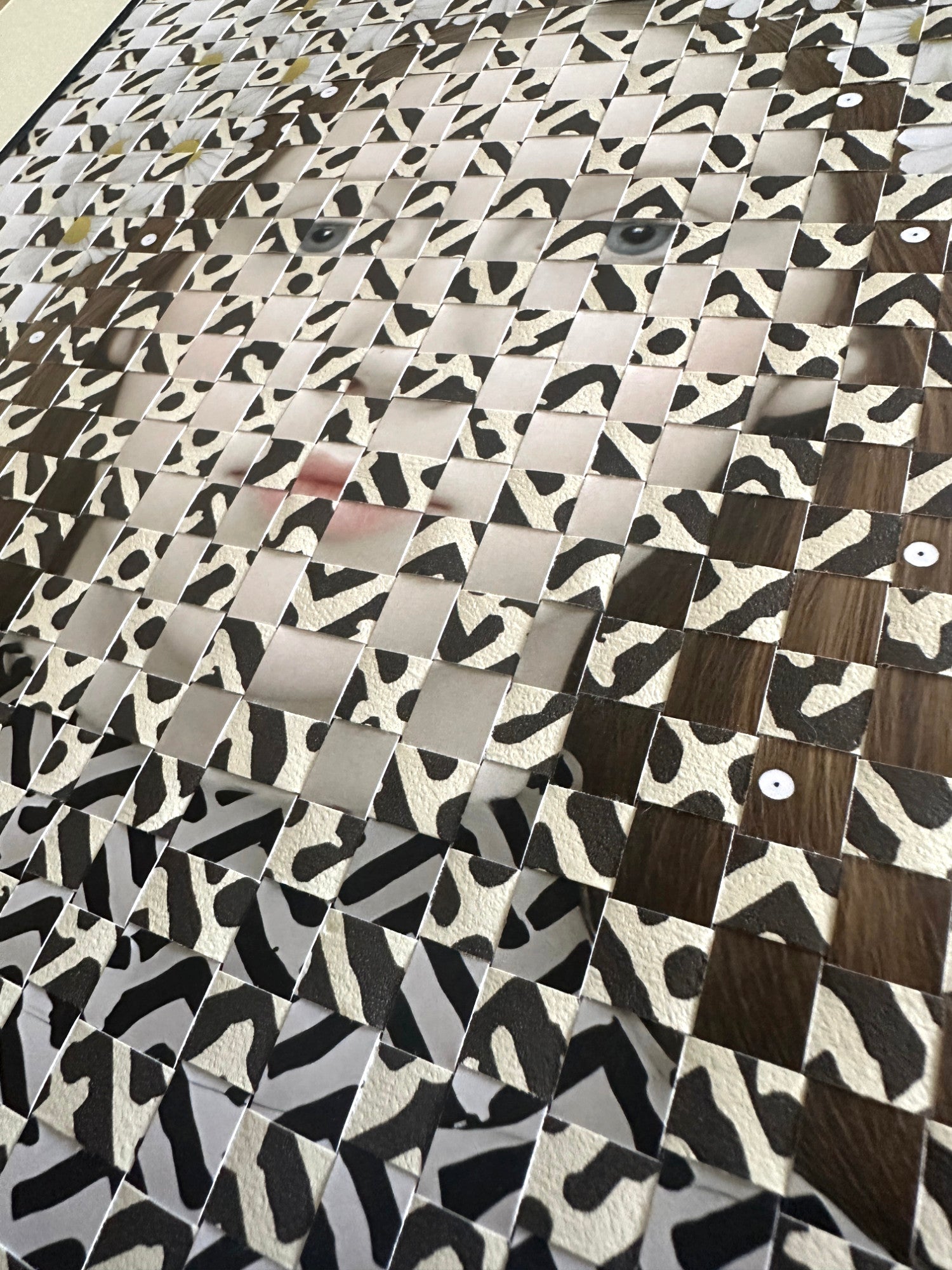 Patterned material with a mix of brown, black, and white woven with a portrait of a girl.