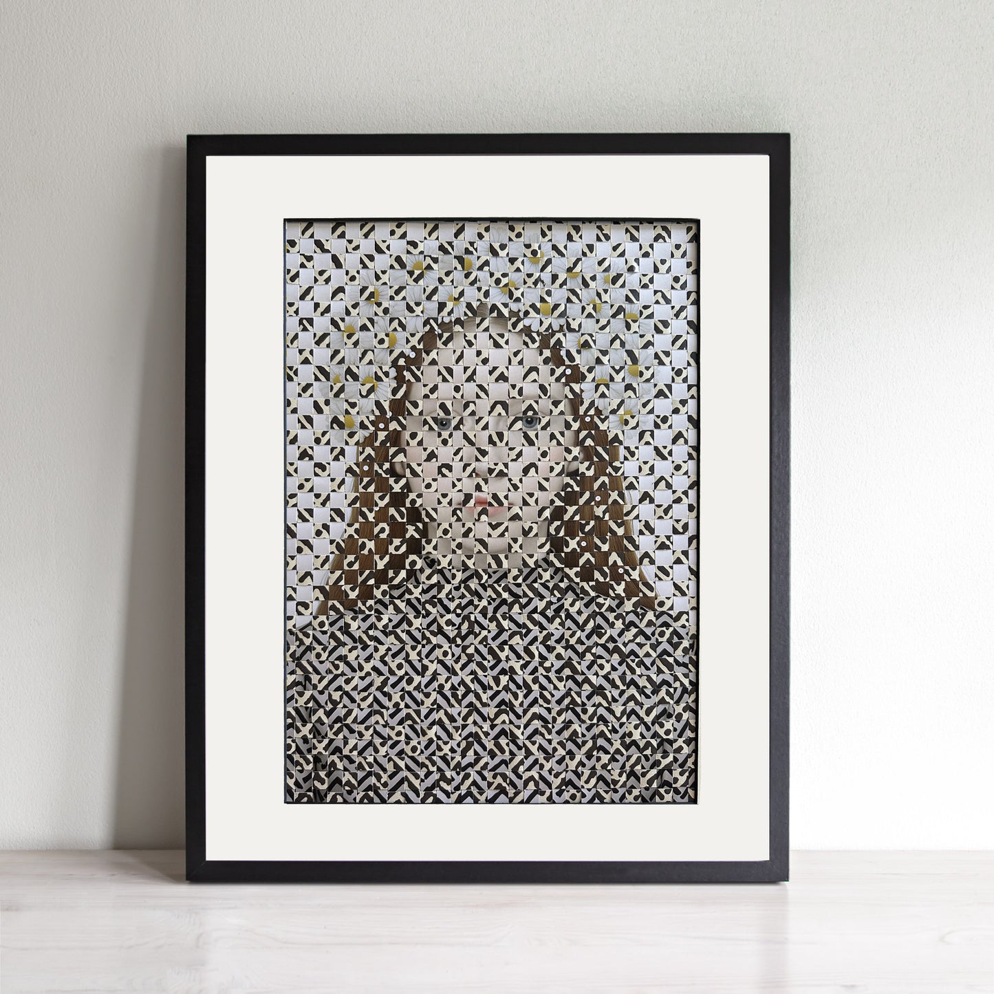 Framed abstract woven art with geometric pattern on a white wall