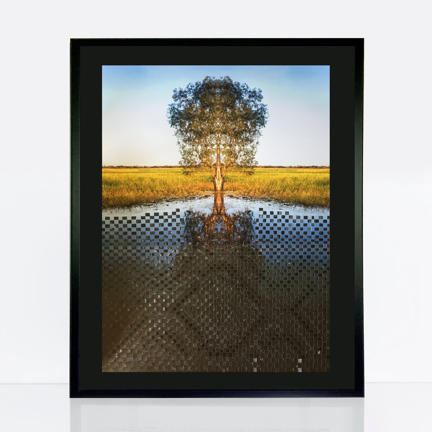 solitary gum tree stands on the bank of a river. The bottom half of the image has been woven with recycled decorative black paper