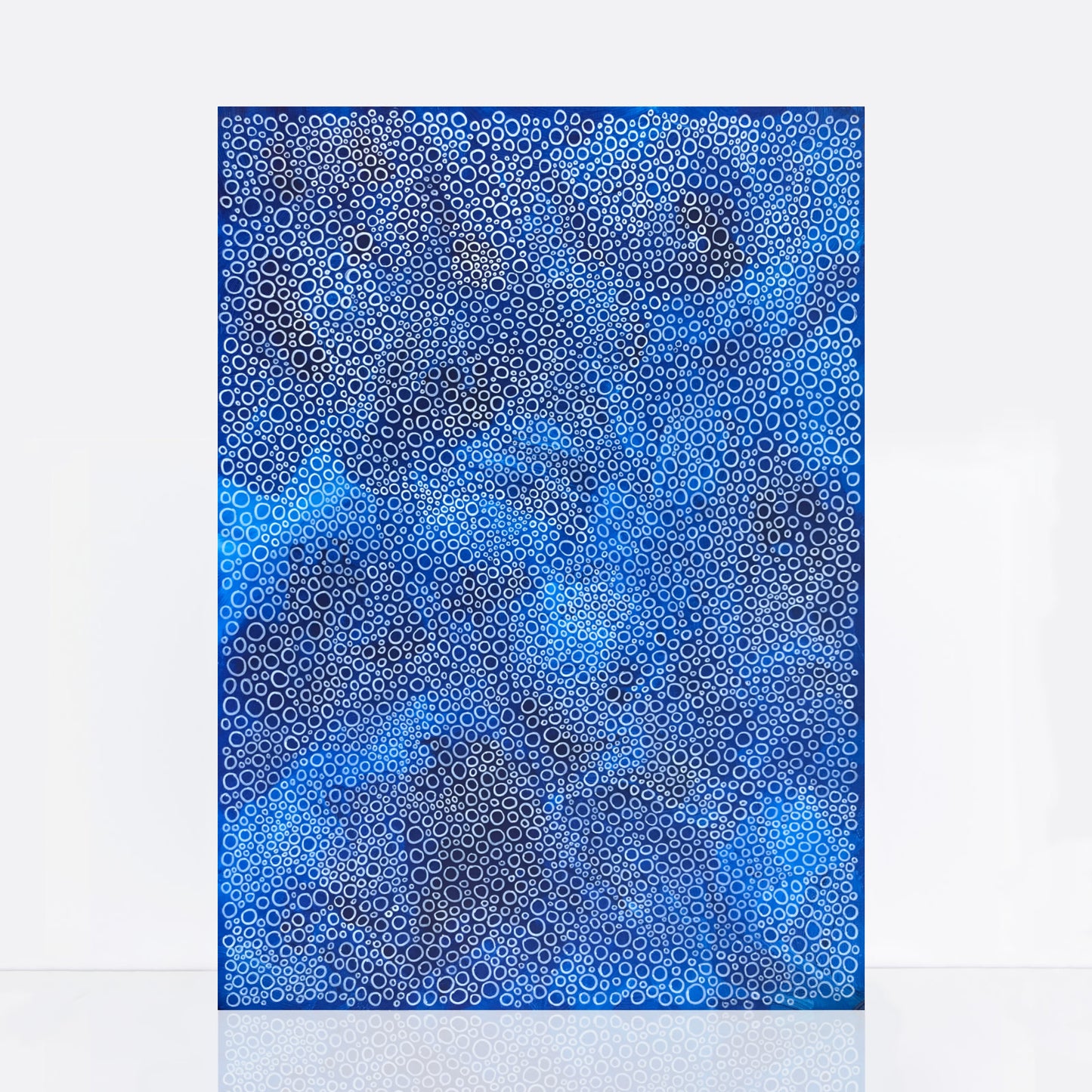 blue artwork features a rich blue background with intricate white circles of varying sizes that resemble sea bubbles and foam