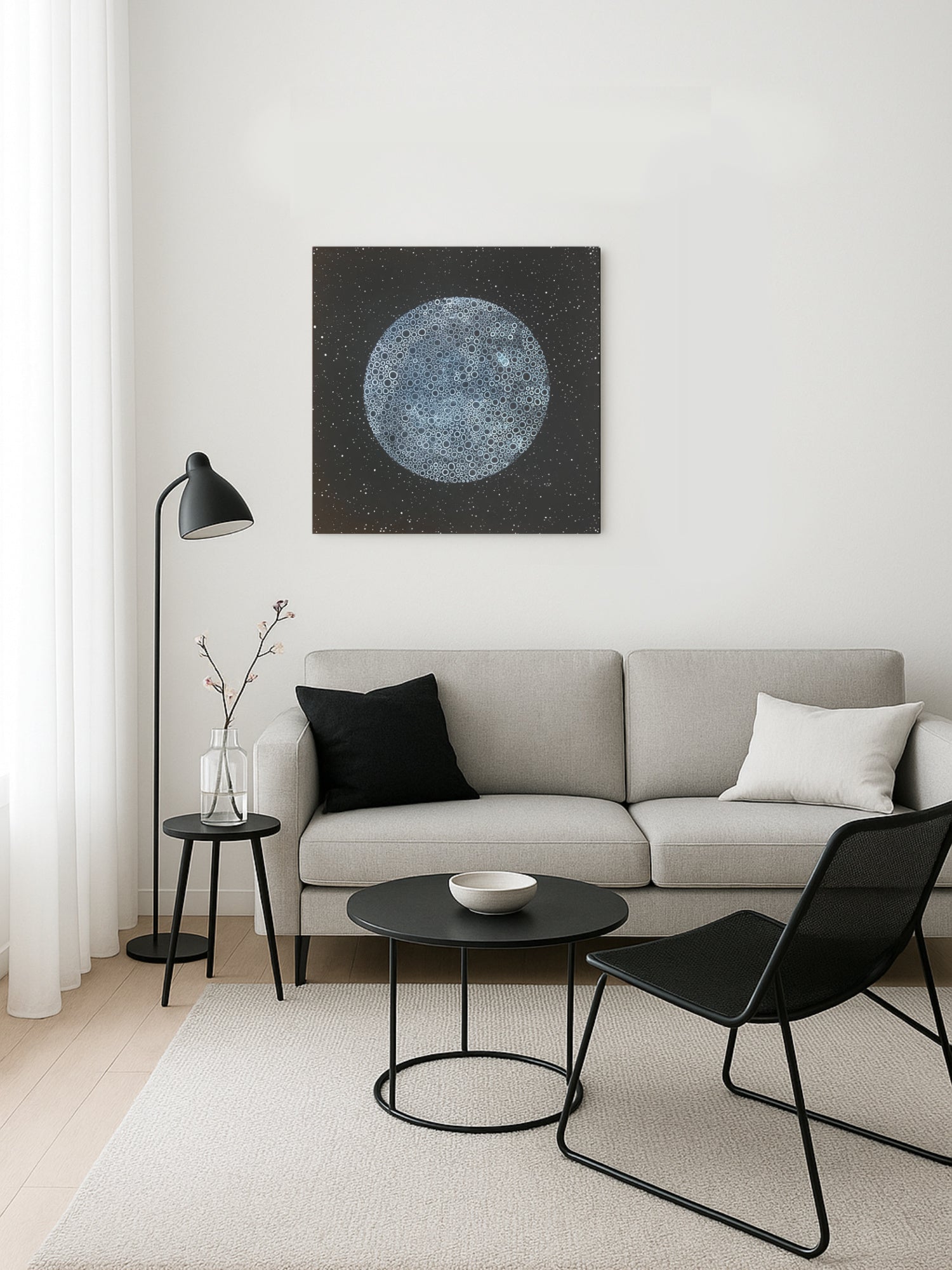 Modern living room with a gray sofa, black chairs, and a wall art piece.