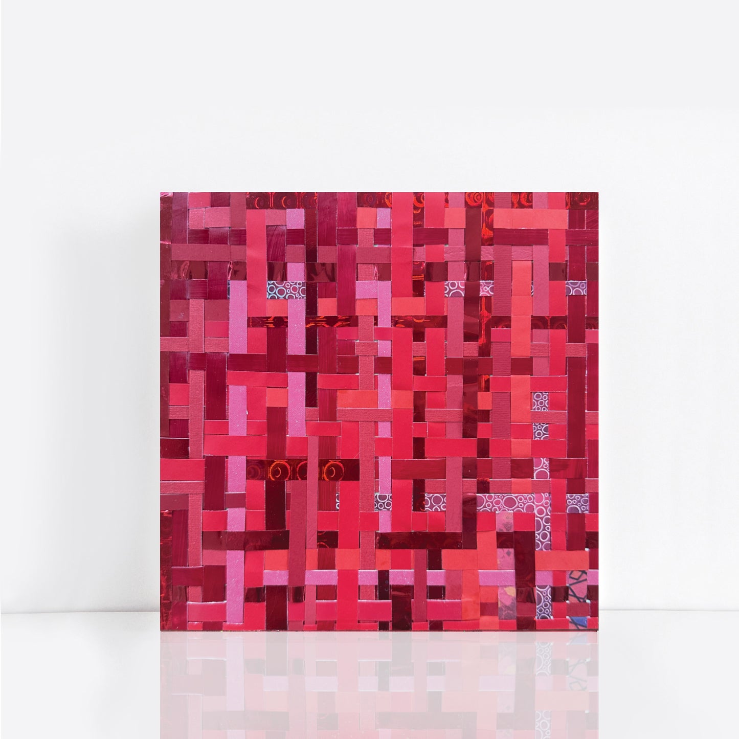 Artwork with a red geometric woven pattern made from recycled paper
