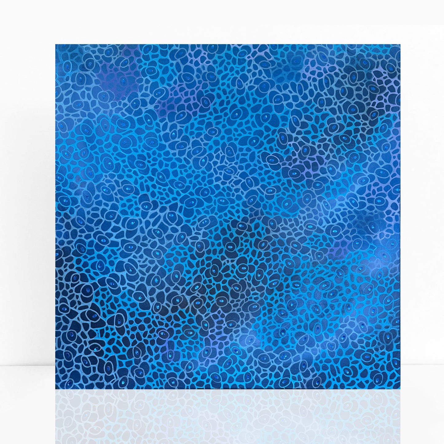 abstract acrylic painting that features intricate layers of rich blue tones. The surface is textured with tiny, hand-cut pieces of shimmery blue paper