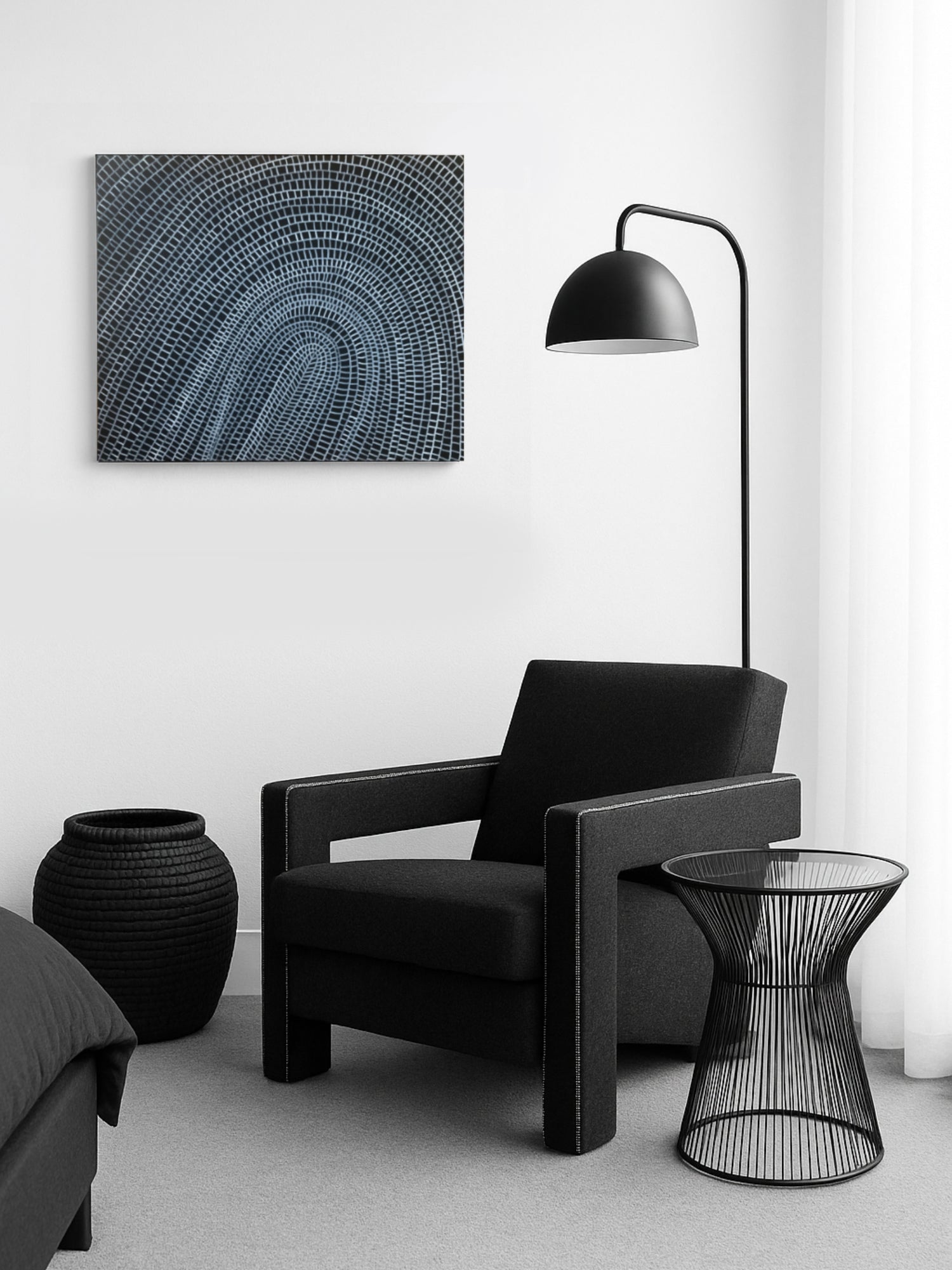 Modern bedroom with black armchair, side table, and abstract wall art.