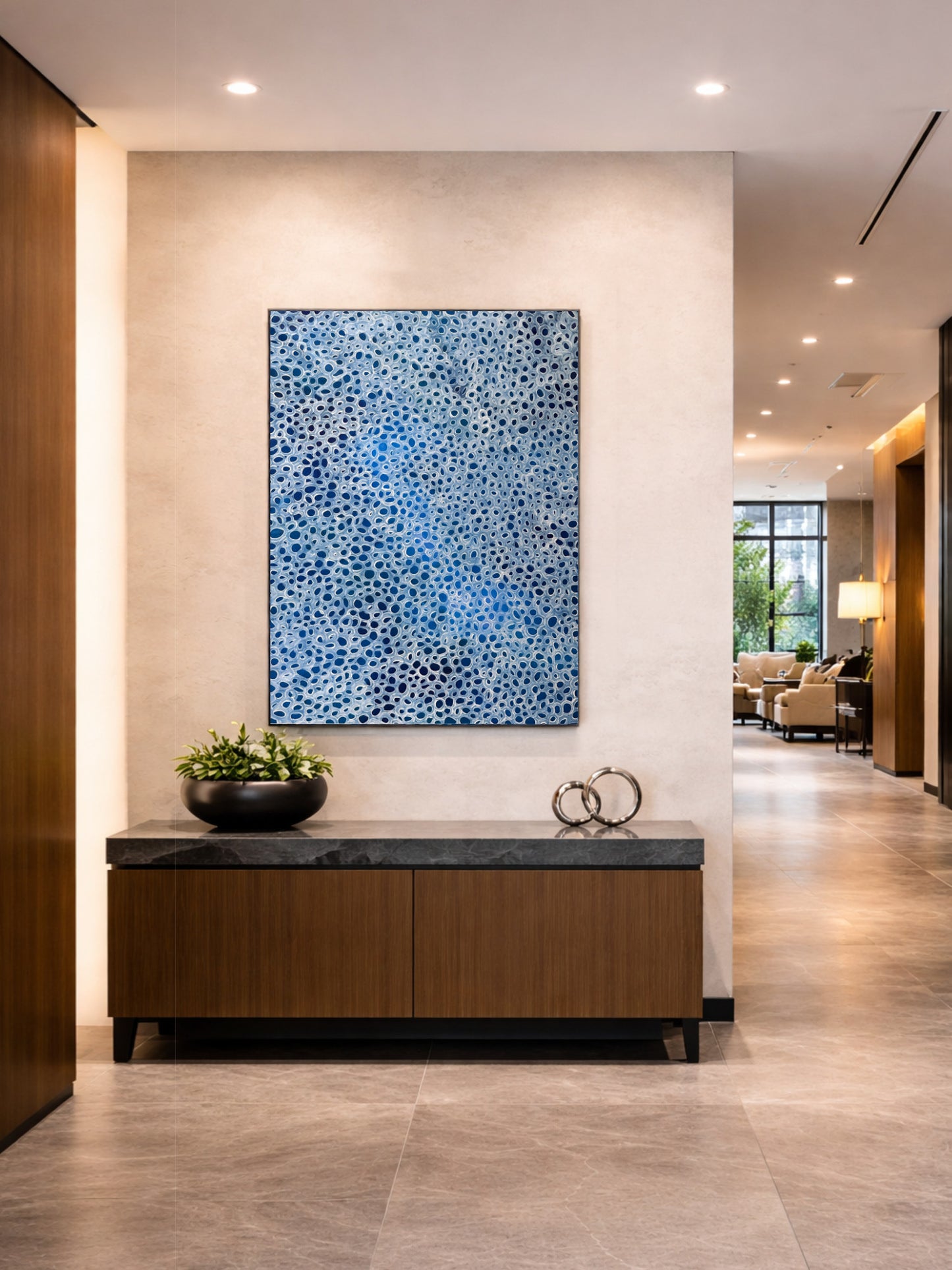 Blue and white abstract painting with organic pattern, displayed in a modern corporate office hallway above a timber console with clean, minimalist commercial styling.